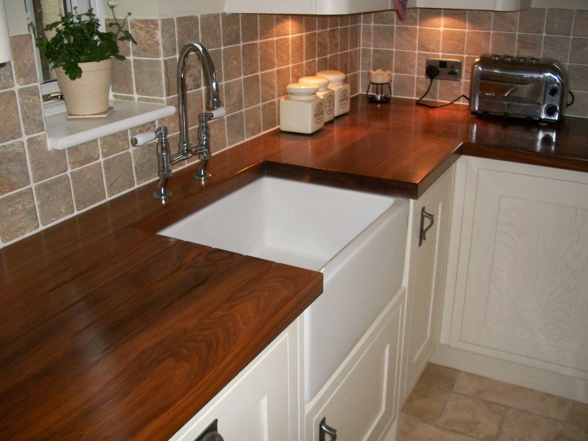 Walnut worktops with Belfast sink and chrome bridge tap in a cream shaker kitchen