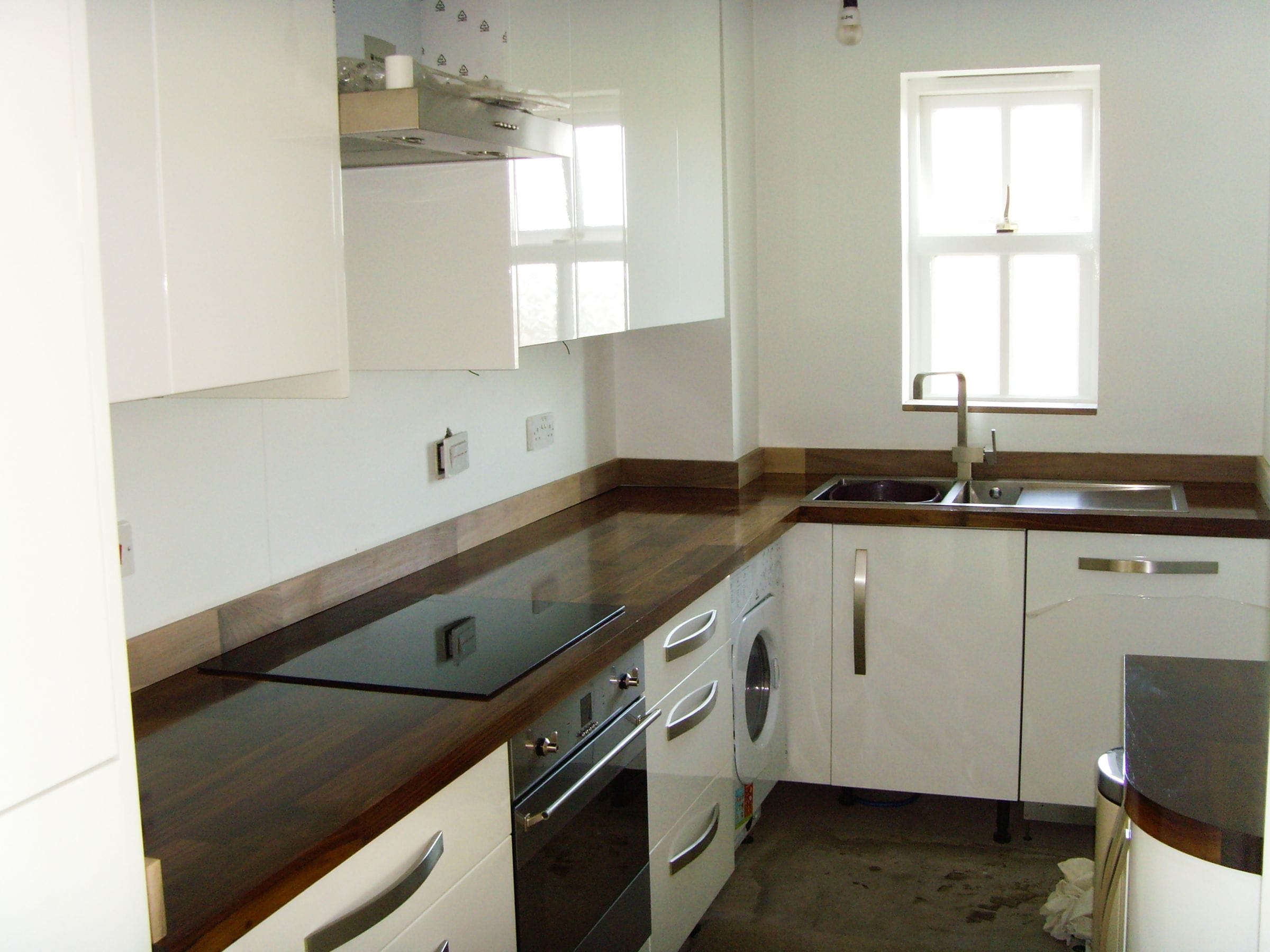 Walnut plank worktops with inset hob and stainless sink in a white gloss kitchen