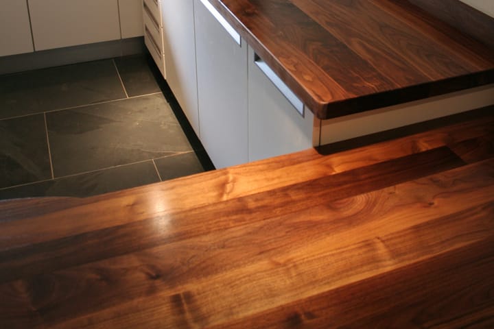 Close-up of walnut worktop grain on two levels above slate floor tiles