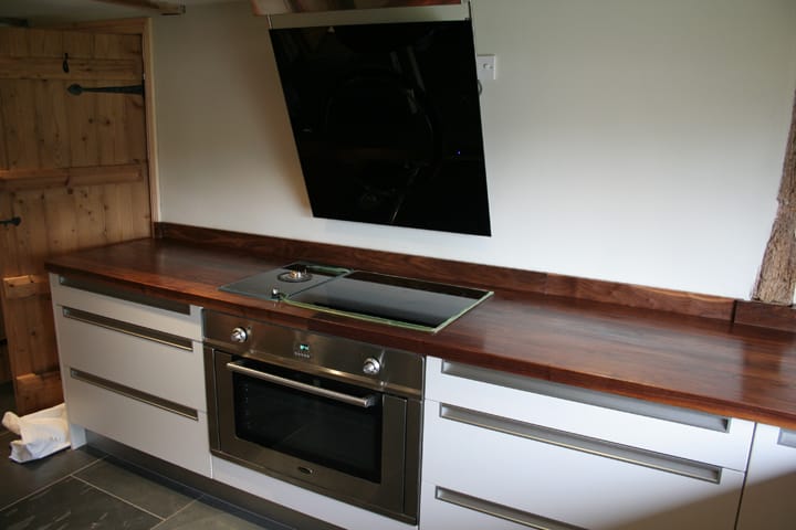 Long walnut worktop with inset hob and angled black extractor in a cream kitchen