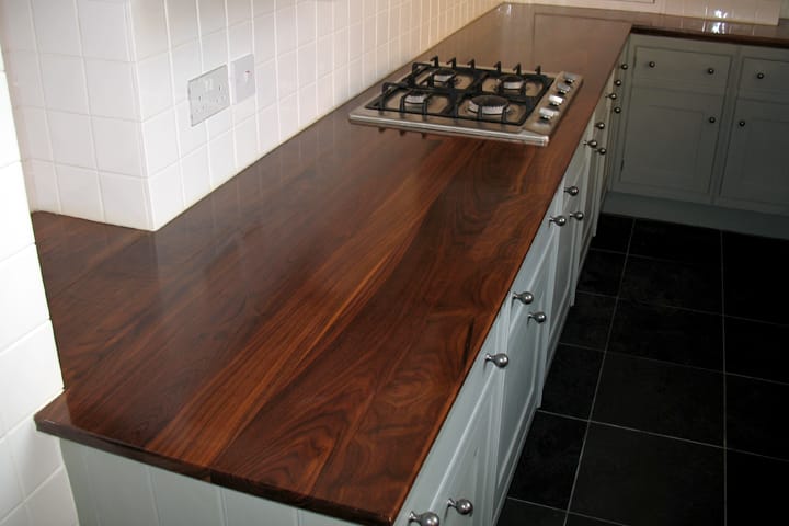 Walnut worktop with stainless gas hob on grey painted cabinets and black floor tiles
