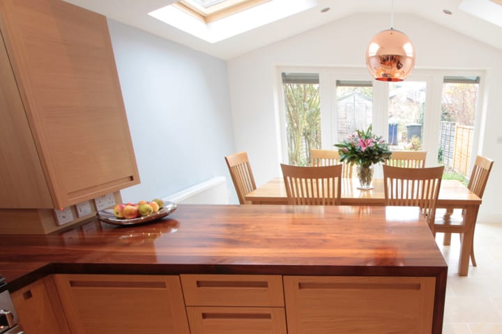 Walnut worktop on oak cabinets with dining table and copper pendant beyond