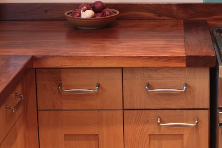 Walnut worktop with breadboard end over oak drawers, bowl of onions on top