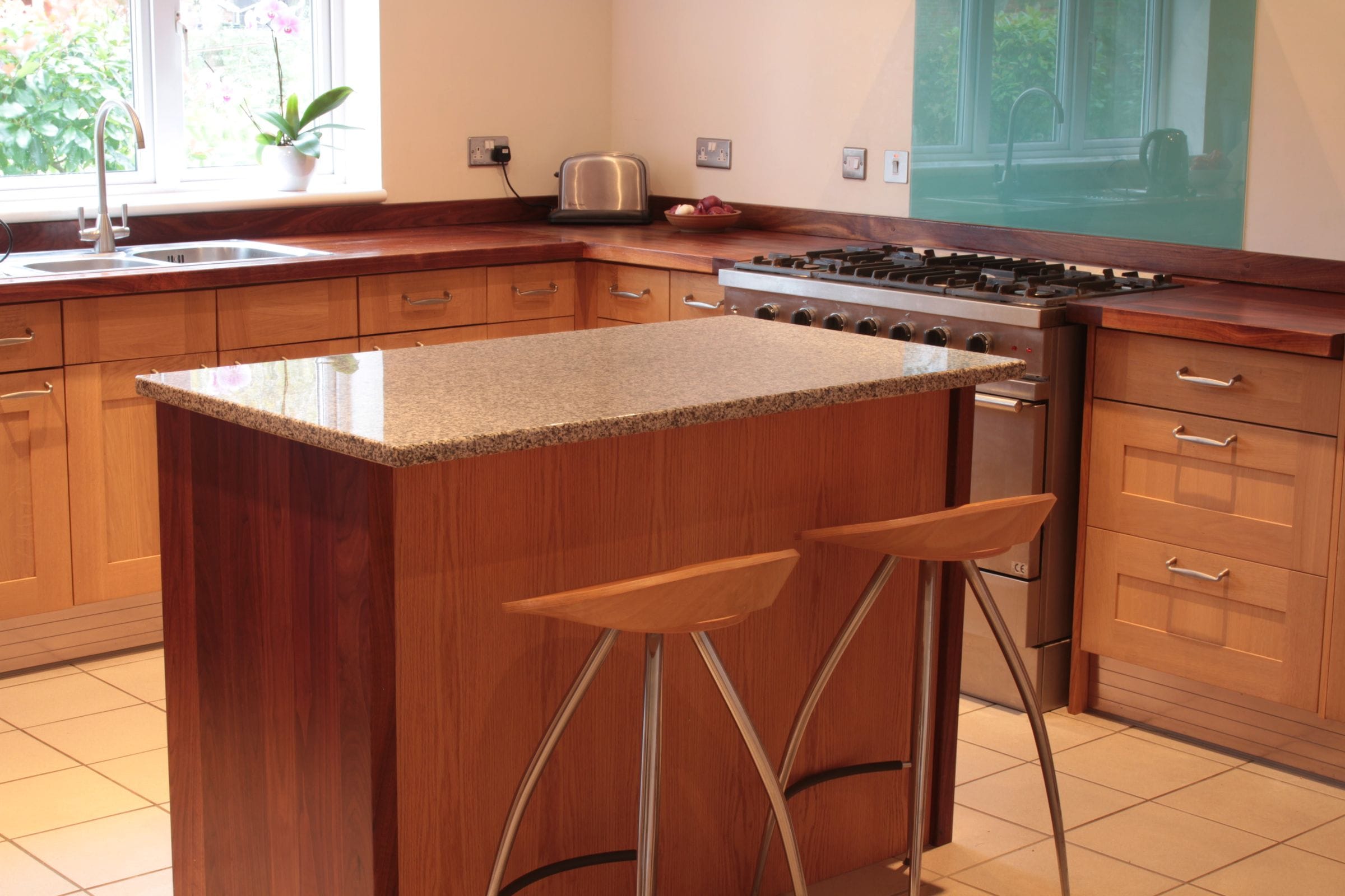 Walnut worktops and granite-topped island with bar stools in an oak kitchen