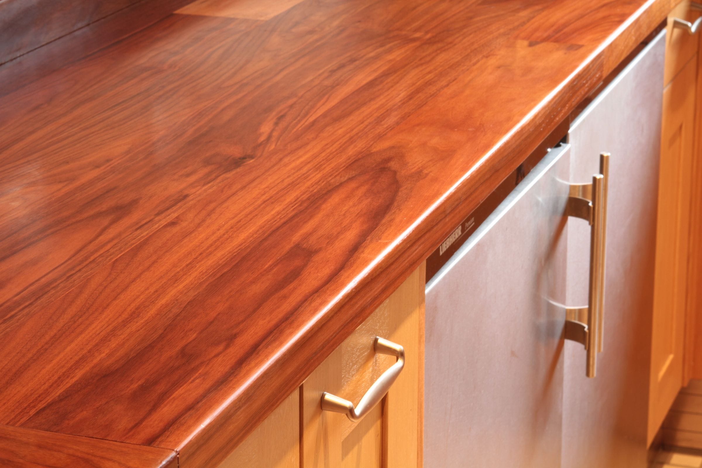 Close-up of swirling walnut grain on a worktop edge above oak cabinets