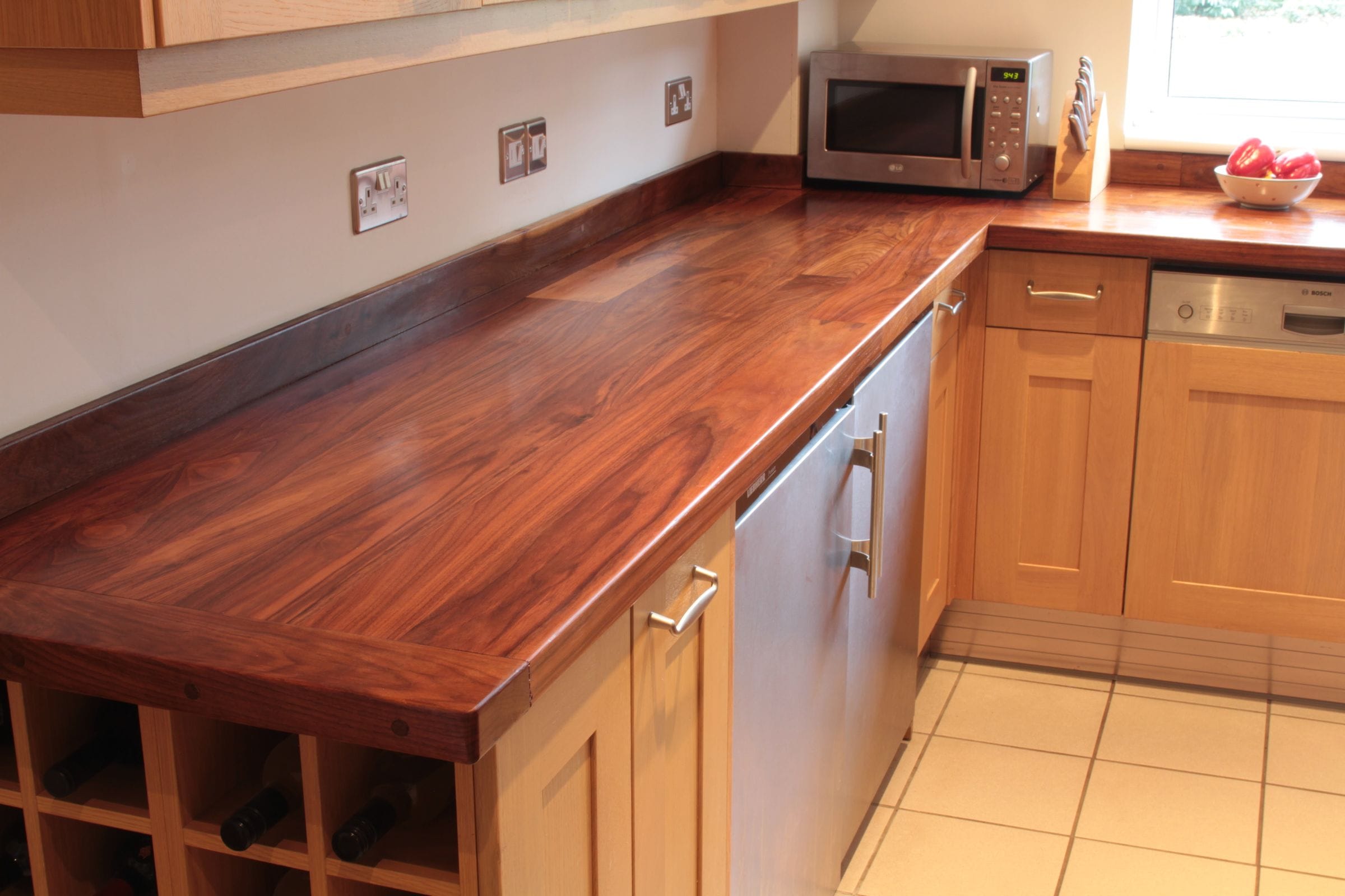 Walnut worktop with framed ends over oak cabinets and integrated fridge