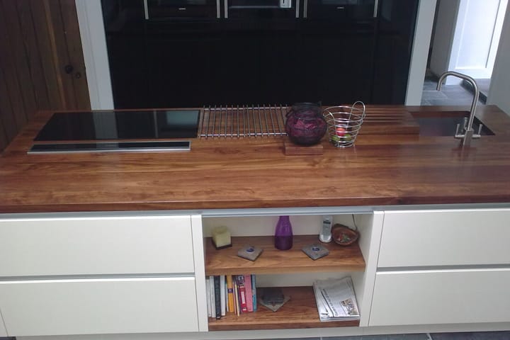 Walnut worktop island with integrated hob, stainless trivet and sink over cream cabinets