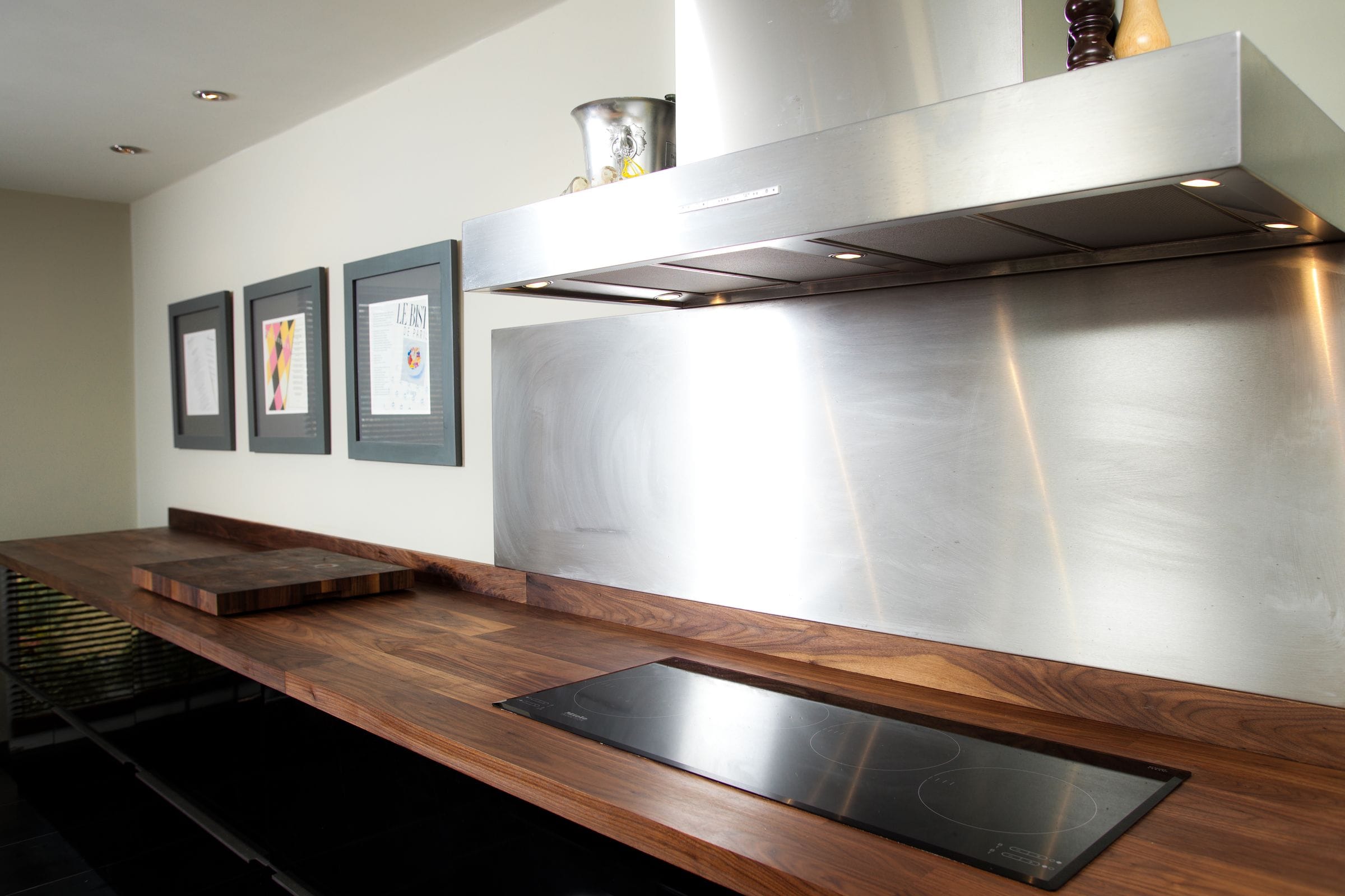 Long walnut worktop with inset induction hob, stainless splashback and extractor hood