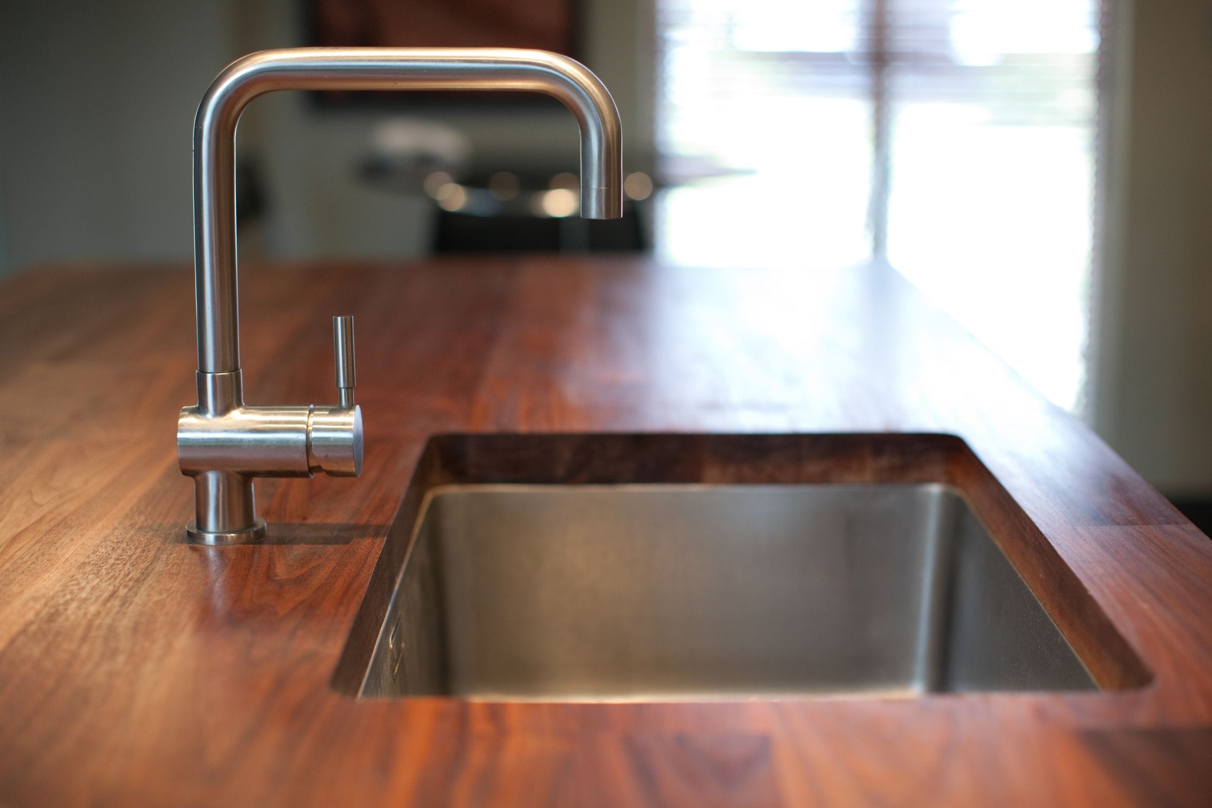 Stainless swan-neck tap and undermounted steel sink in a walnut worktop