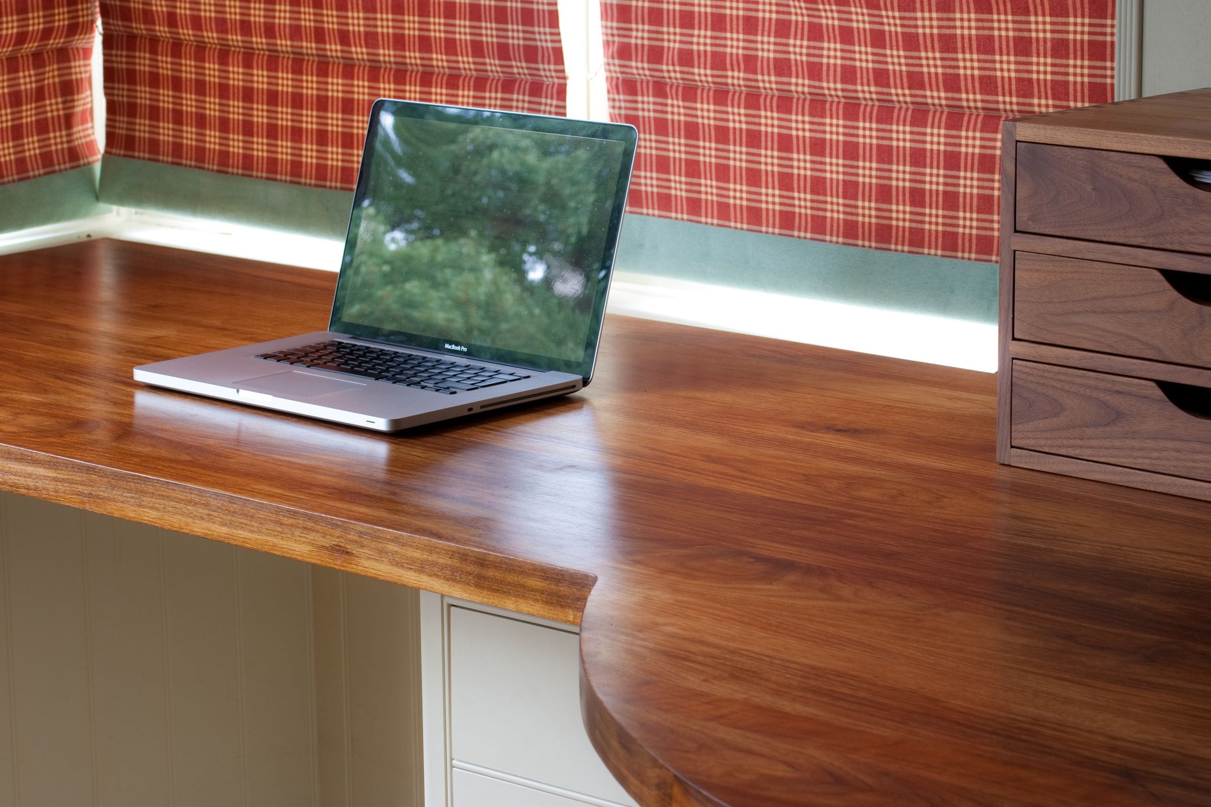 Curved walnut desk top with laptop and matching walnut drawer unit