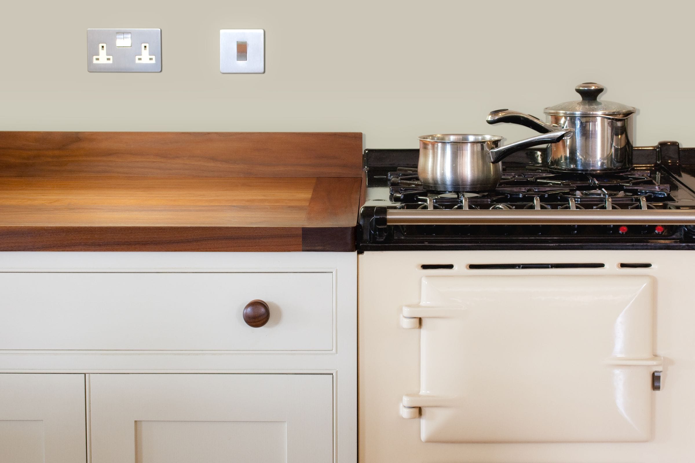 Walnut worktop on cream shaker cabinets next to a cream Aga range cooker
