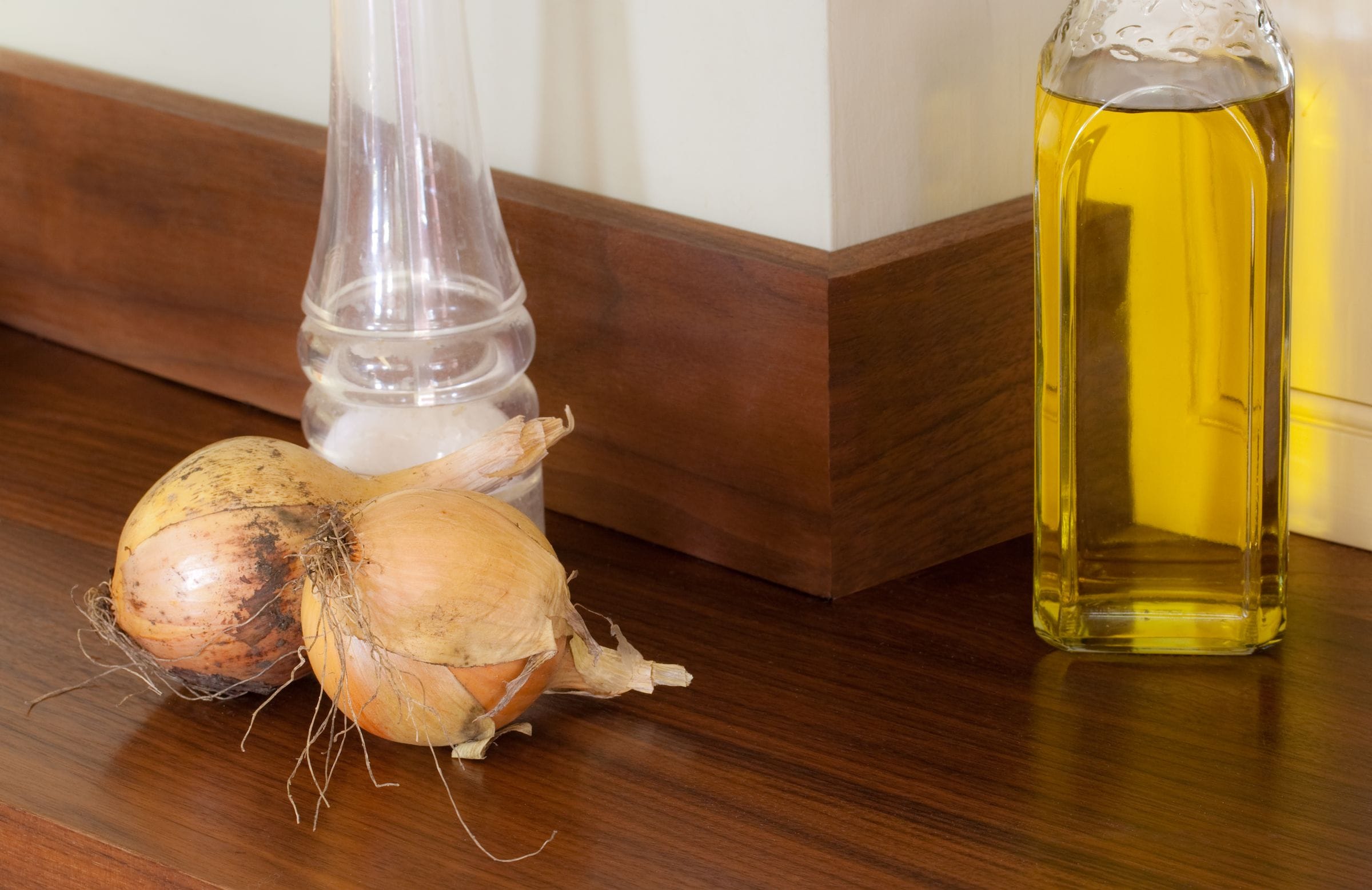 Onions and a bottle of oil on a walnut worktop with matching upstand