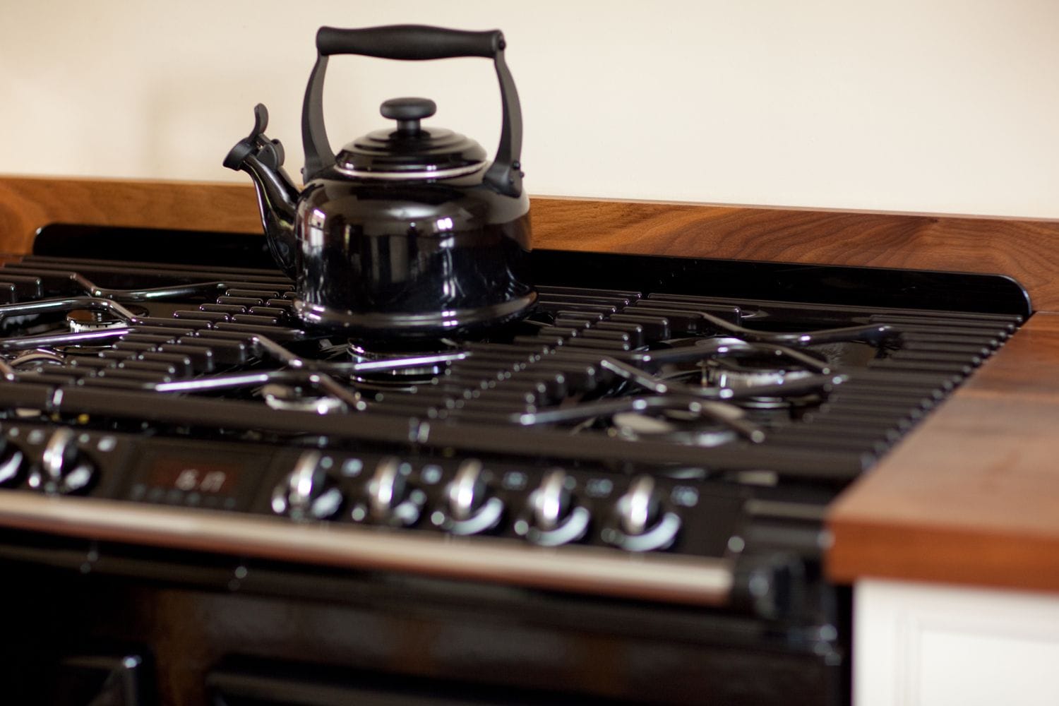 Black kettle on a range cooker hob flanked by walnut worktops