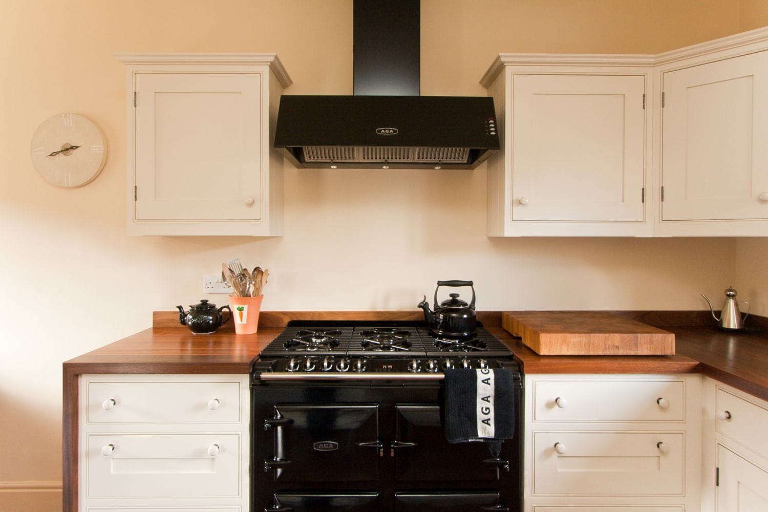 Cream kitchen with black Aga range, matching hood and dark wood worktops