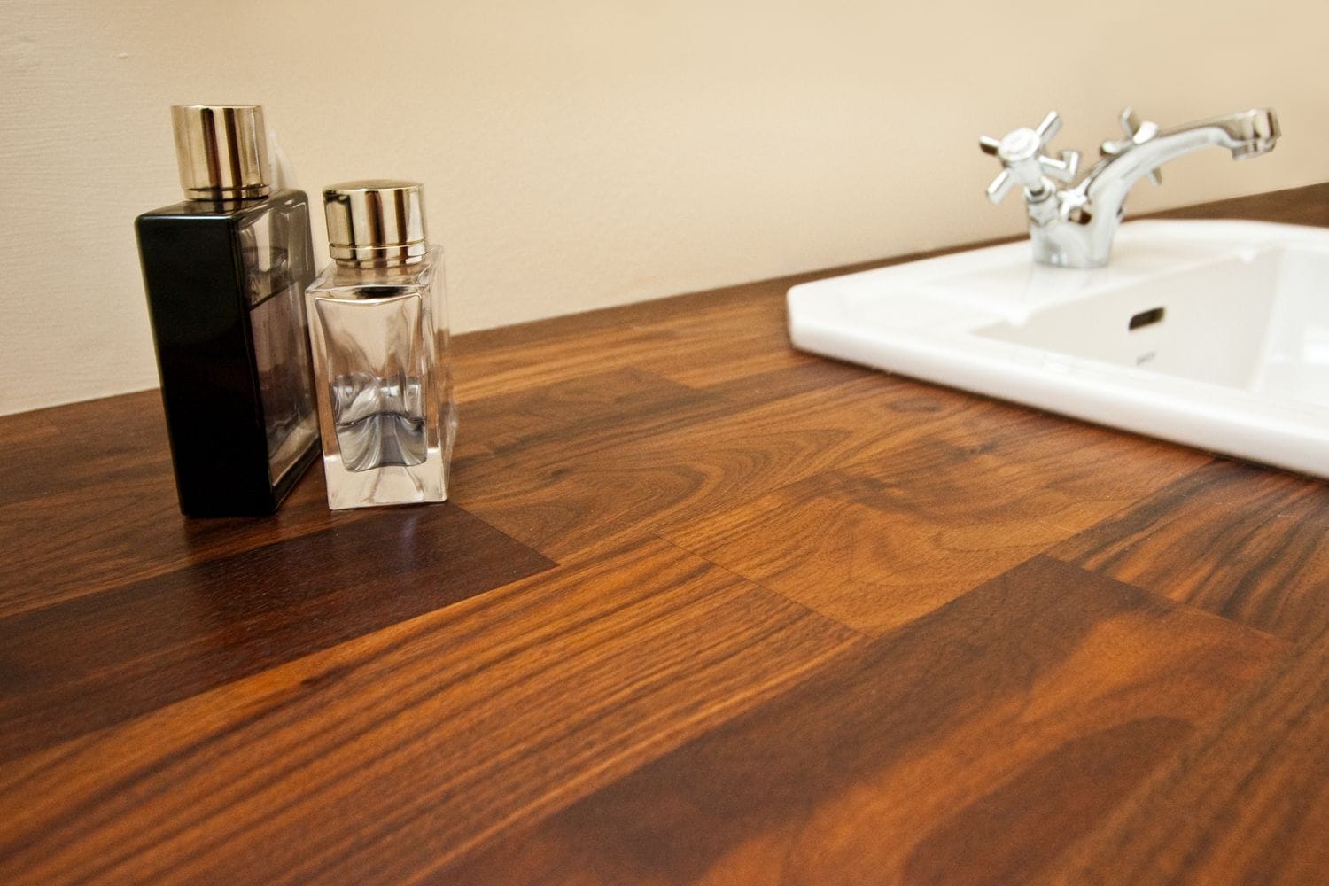 Walnut bathroom countertop with inset white basin and fragrance bottles