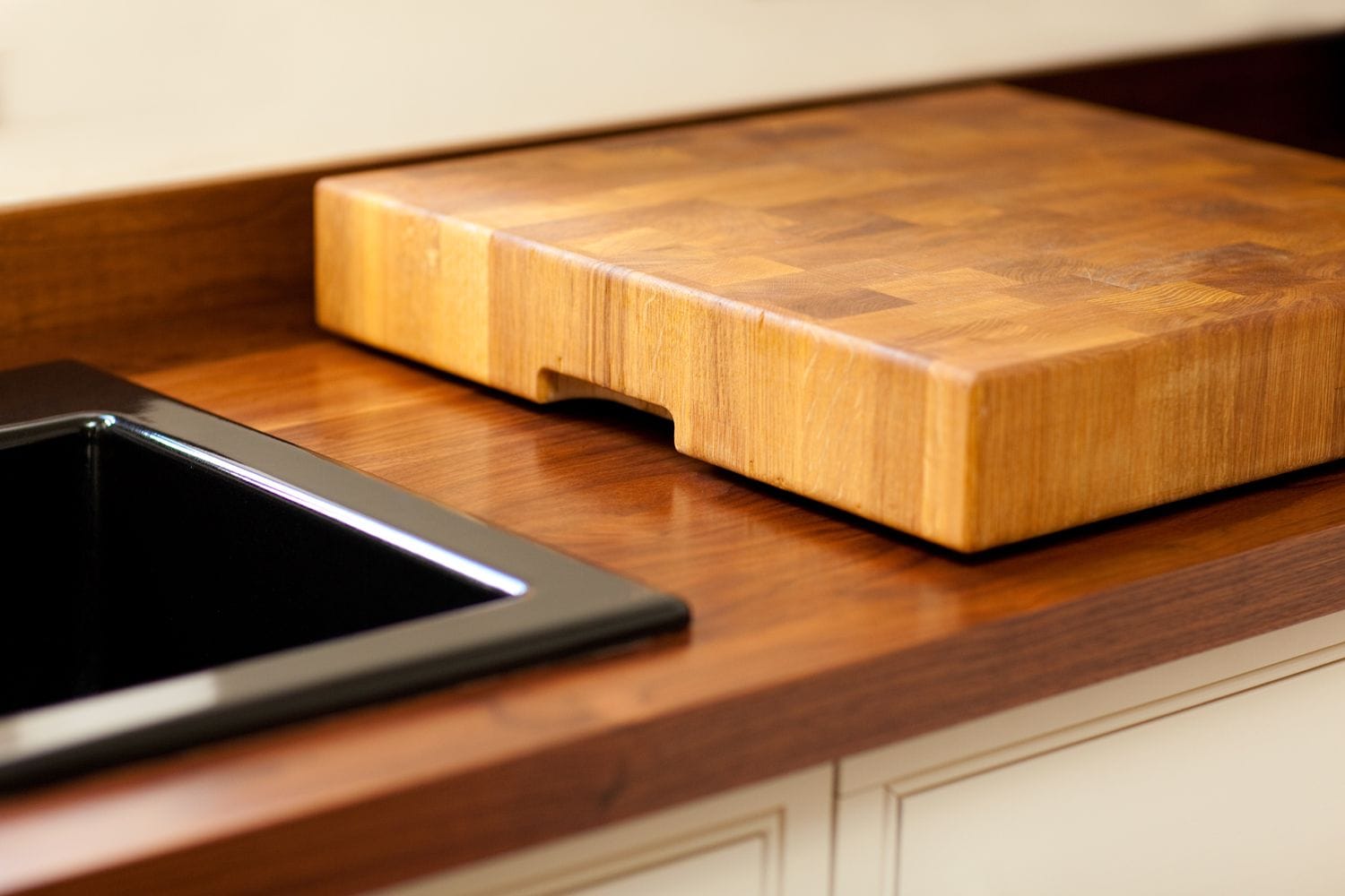 End-grain oak chopping board on a walnut worktop beside a black inset sink