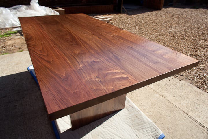 Freshly oiled walnut dining table drying outdoors in sunshine at the workshop