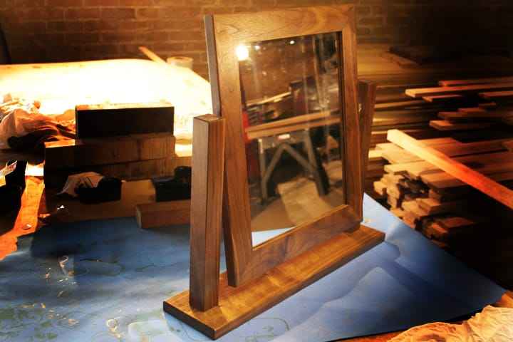 Handmade walnut-framed swing dressing table mirror on the workshop bench