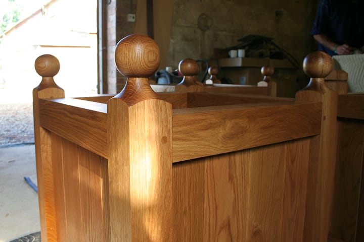Close-up of a solid oak garden planter with turned ball finials in the workshop