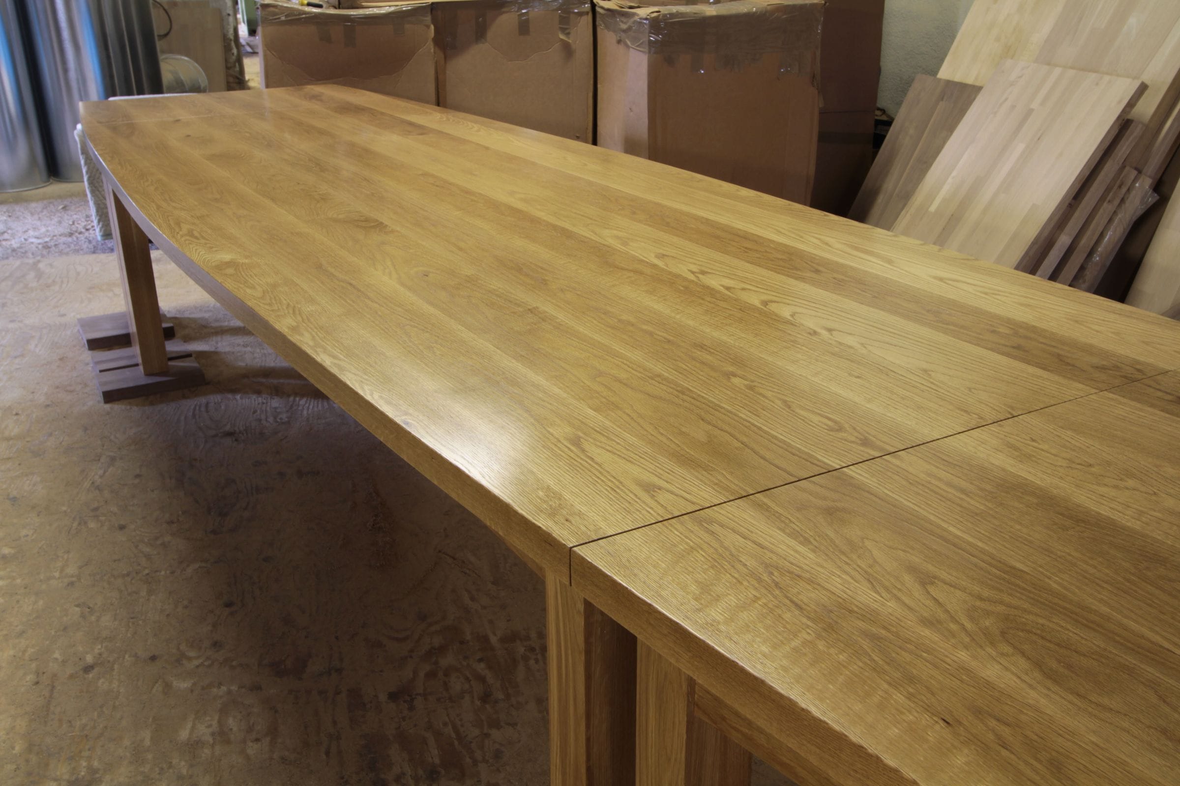 Long oiled oak boardroom table with curved ends awaiting delivery in the workshop