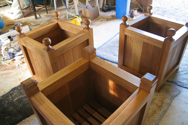 Three handmade oak garden planters with ball finials assembled in the workshop