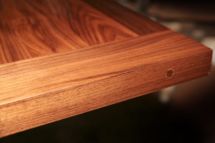 Close-up of a pegged breadboard end joint on a walnut table top