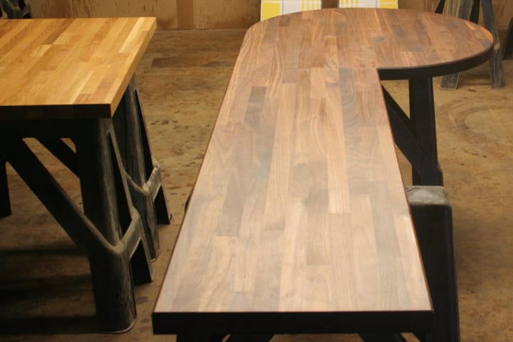 Curved walnut worktop on trestles in the workshop beside an oak worktop