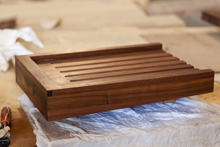 Handmade walnut bread board with grooved slatted top on the workshop bench