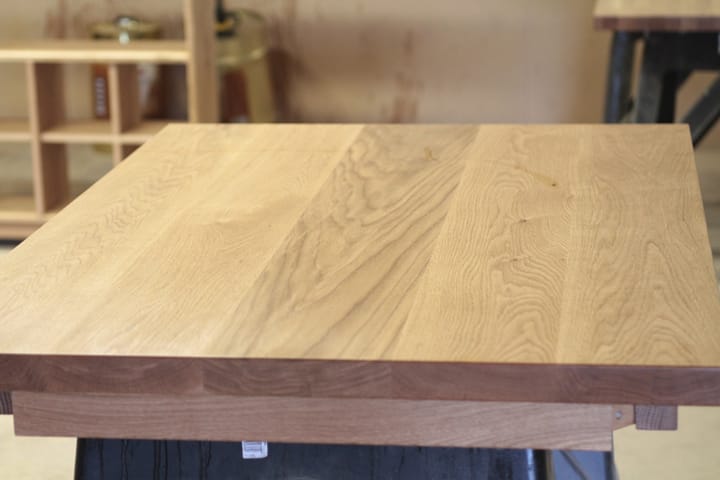 Square oak table top with wide planks on a trestle in the workshop