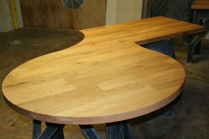 Curved teardrop-shaped oak breakfast bar worktop on trestles in the workshop