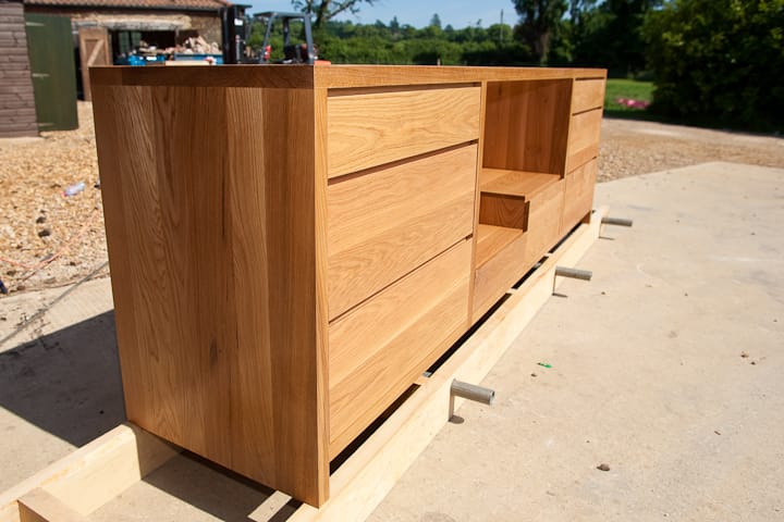 Solid oak sideboard cabinet with drawers being finished outdoors at the workshop