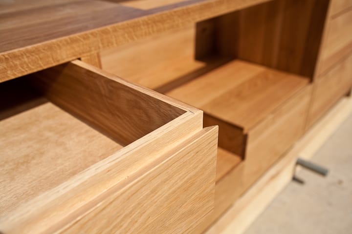 Close-up of a dovetailed oak drawer open in a handmade cabinet