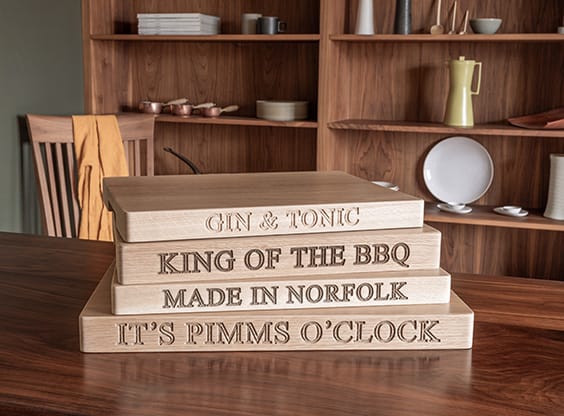 Stacked oak chopping boards engraved with phrases like King of the BBQ