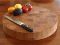 Round oak end grain chopping block with knife, avocado and tomatoes