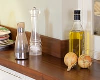 Dark wood worktop and matching upstand with oil bottle, grinders and onions