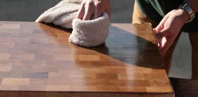 Hands rubbing oil into an end grain chopping board with a cloth