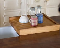 Grooved oak draining board holding milk bottles and a bowl beside a sink