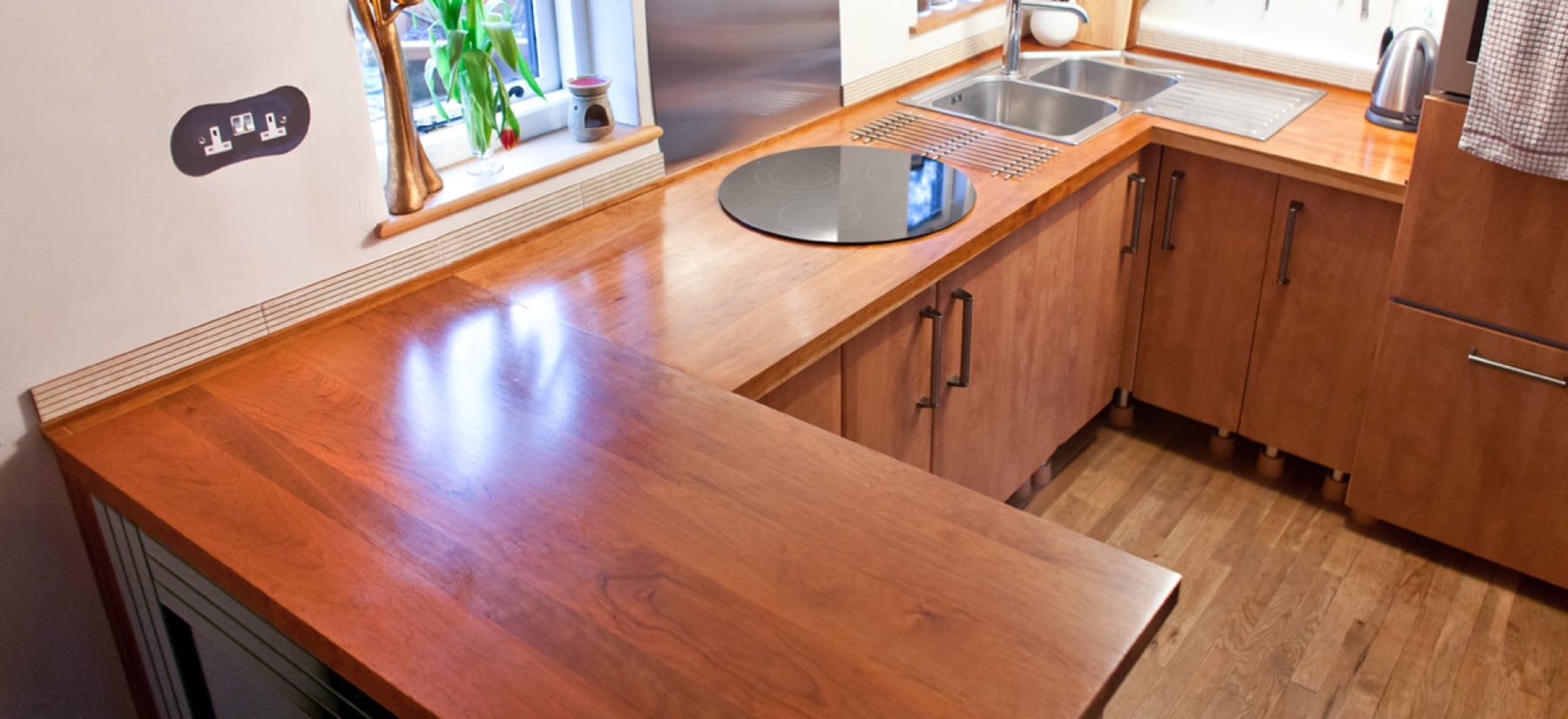 Cherry super stave worktops in an L-shaped kitchen with induction hob and inset sink