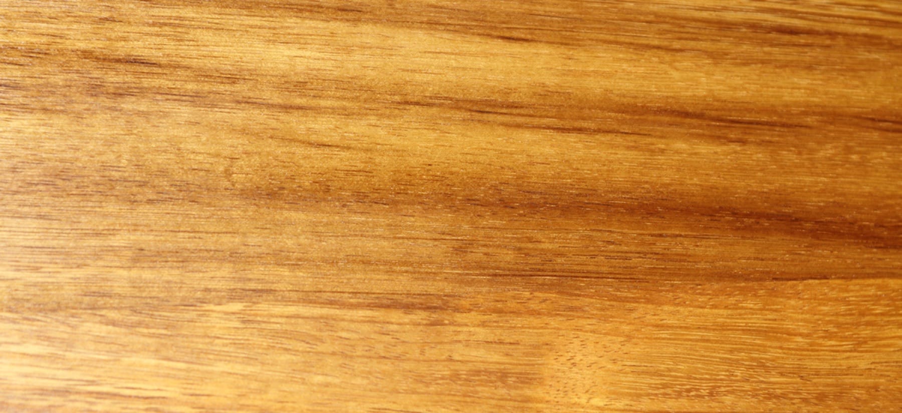 Golden-brown grain of an oiled iroko worktop in close-up
