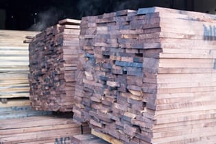 Stacked American walnut planks stickered for drying at the timber yard