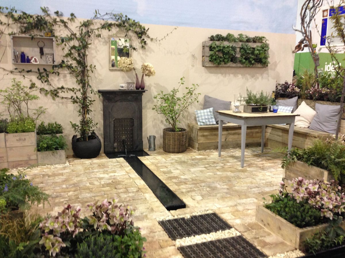 Courtyard garden display with stone paving, wall planters and outdoor seating