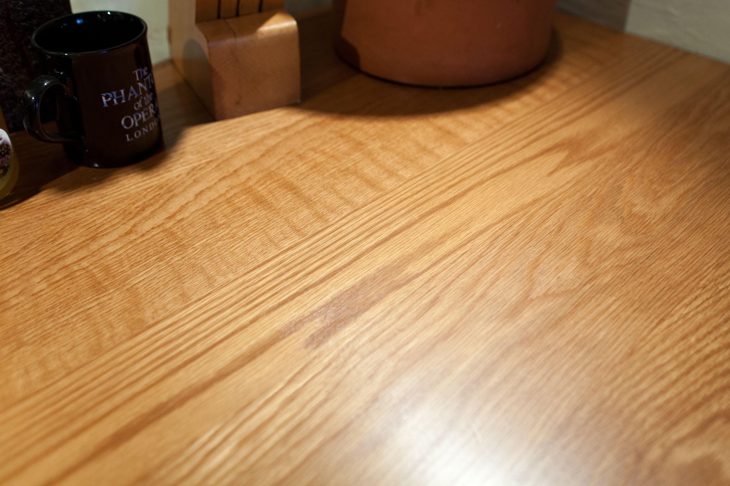 Warm golden oak worktop with a mug and knife block on top