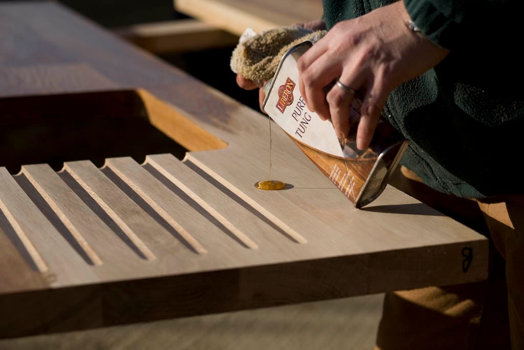 Pouring pure tung oil onto the drainage grooves of an oak worktop
