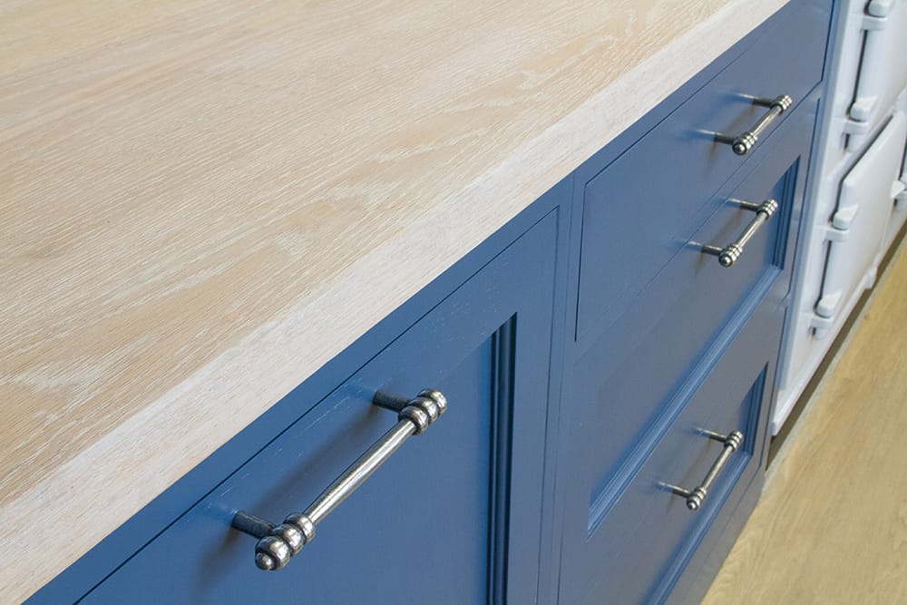 Whitewashed oak worktop above blue painted drawers with pewter handles