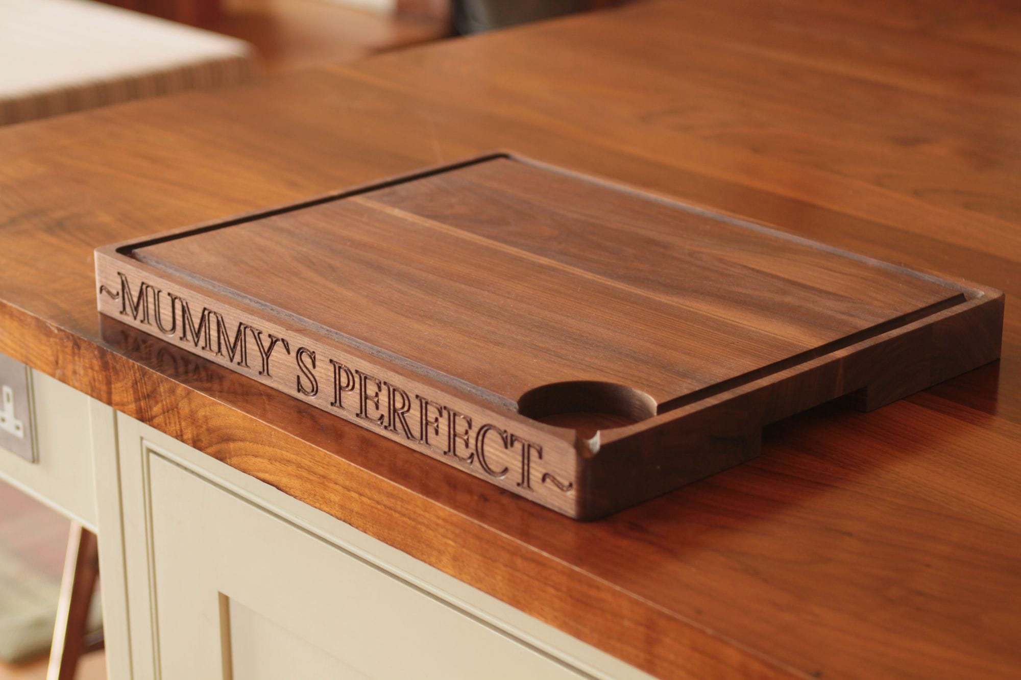 Walnut carving board engraved Mummy's Perfect resting on a wooden worktop