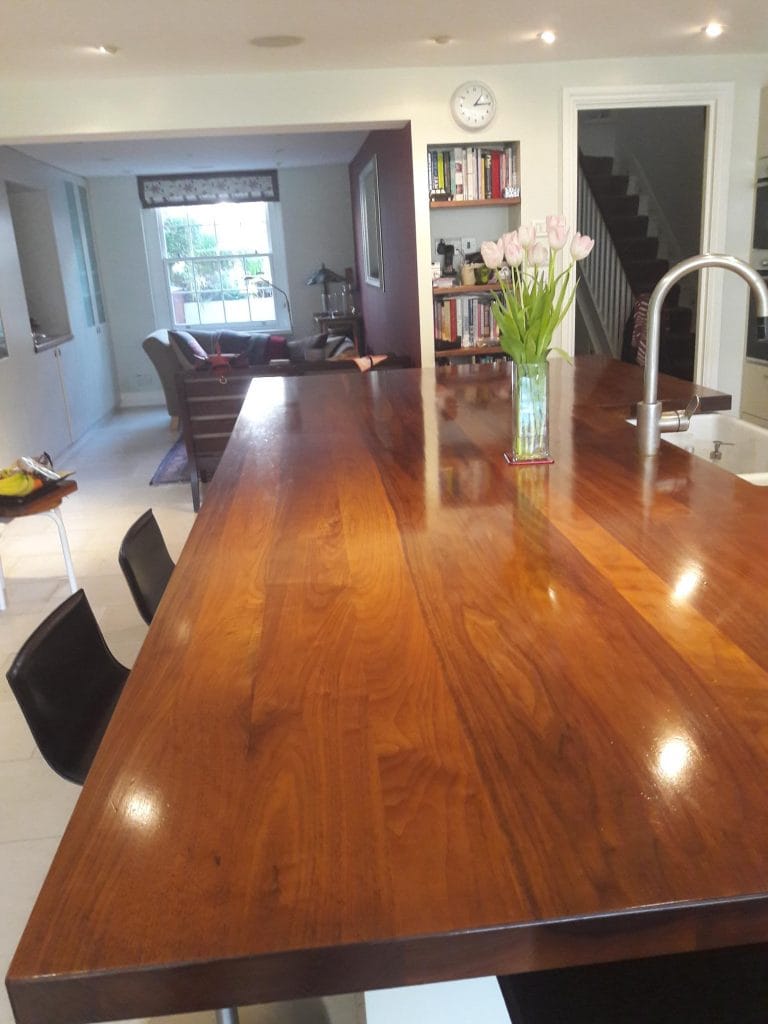 Oiled walnut kitchen island worktop with tulips and sink, still glowing after ten years of use