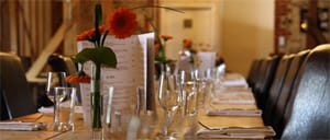 Long dining table set with glasses and orange gerberas at Cafe du Soleil