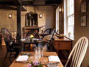 Wooden dining tables by an open fire in The Crown's beamed dining room