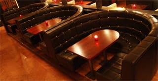 Curved leather booth seating with dark wooden tables at Revolution Bar