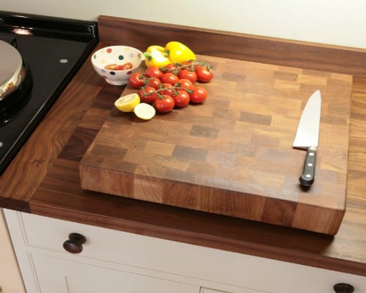Walnut end grain chopping block with knife, tomatoes and lemons on a worktop